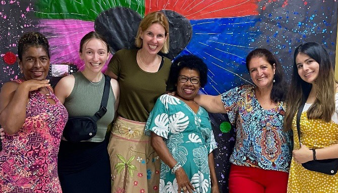 People smiling in front of a colourful wall.