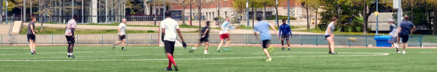 Queen's students running on the soccer field during a match.