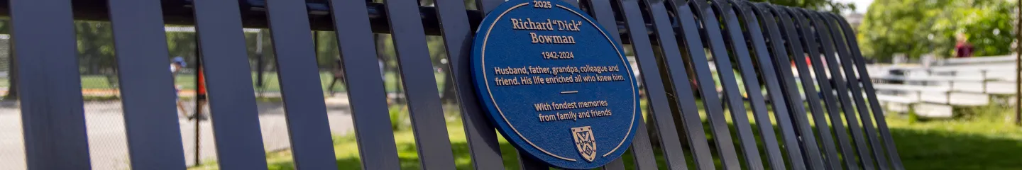 A blue plaque affixed to a metal bench, providing historical information about the location or individual commemorated.
