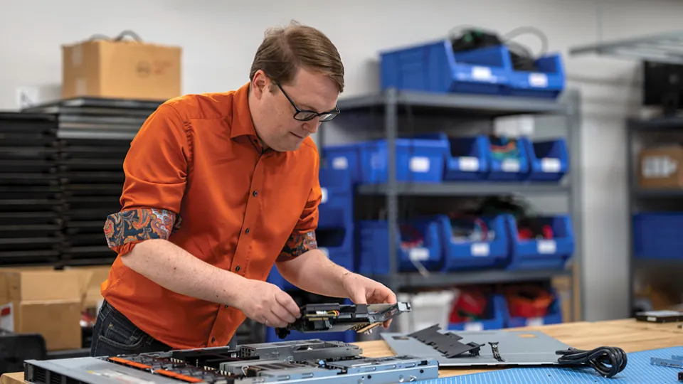 Photo of Dr. Ryan Grant assembling computer hardware at a workbench.
