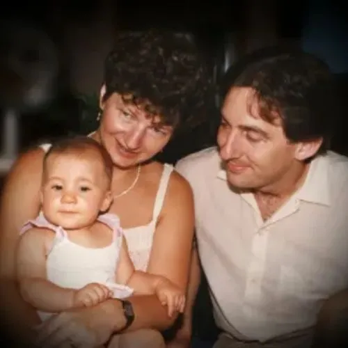 A man and woman sit on a couch, holding a baby, in a heartfelt tribute to Al Kannegieter's memory.