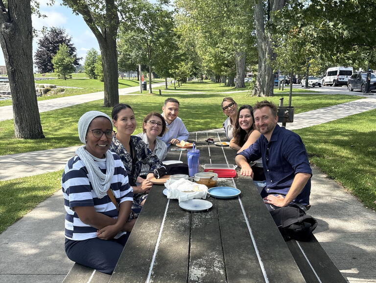 A group of people have lunch on a picnic table outdoors