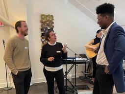 Three people stand and chat.