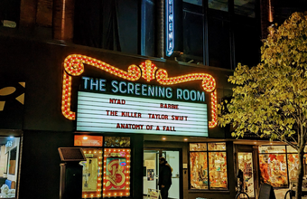 Illuminated marquee of The Screening Room displaying names including 'Taylor Swift' and movie titles.