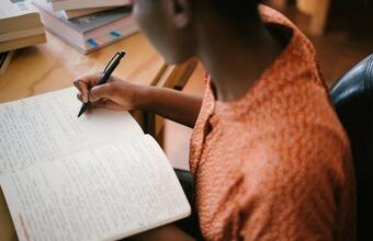 A photo of a person writing by hand in a notebook.