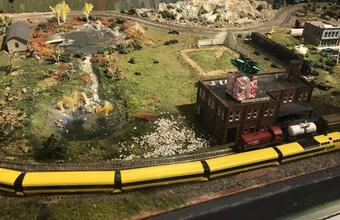 Model of the VIA Rail in a vibrant landscape of fields, trees, rocks, and buildings