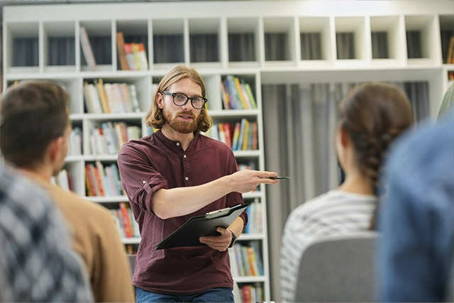 A teacher standing in front of students and teaching in a classroom