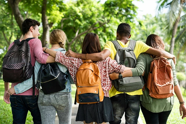 A group of five teens with backpacks walking away
