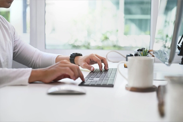 A person typing at a desk on a laptop
