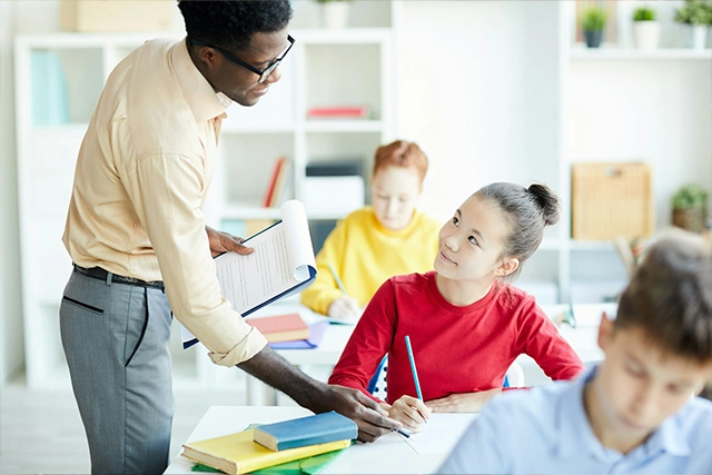 A classroom teacher point at a student's book