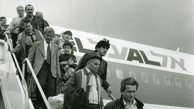 A black and white photograph of Jewish people disembarking a plane