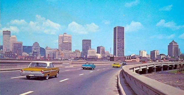 A grainy coloured photograph of 1970s cars driving down a newly built highway