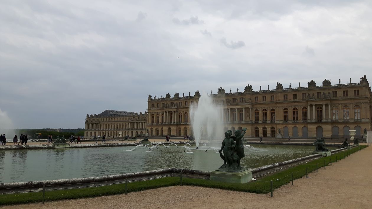 A photograph of the Palace of Versailles in France, with a grand water fountain on the lawn