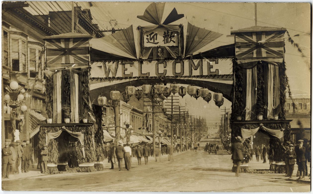 A sepia toned old photograph of a Chinese street arch at Carrall and Pender streets in Vancouver