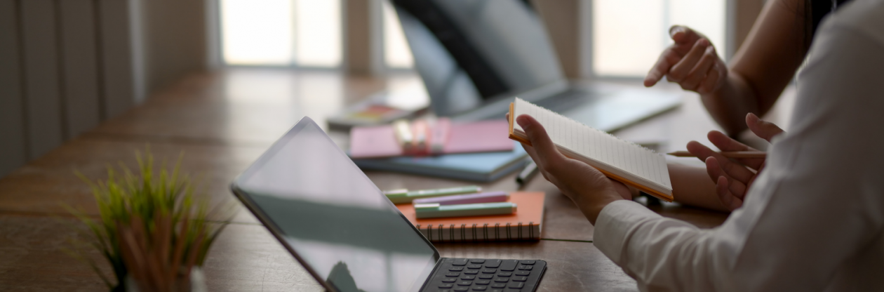 An image of two people in discussion working at a desk.