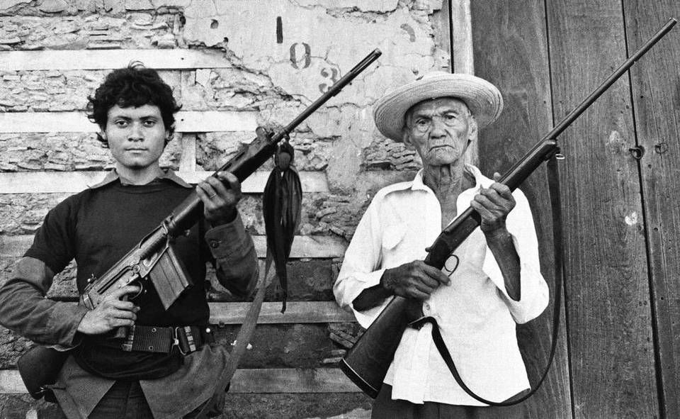 Image of two generations of Latin-American men holding firearms