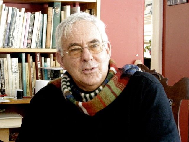 Image of Geoff Smith seated with a bookshelf full of books behind him
