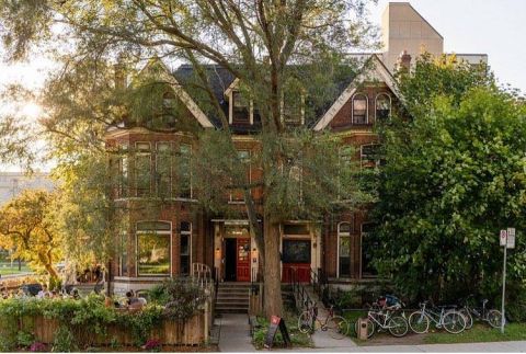 An image of the exterior of the grad club in the summer with green foliage