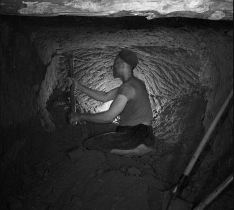 A man mining in a dark cave in Tunisia. 20 February 1960, Redeyef, Tunisia. Photo copyright Gilbert von Raepenbusch, reprinted courtesy of Fonds Beit el Bennani, Tunis, Tunisia
