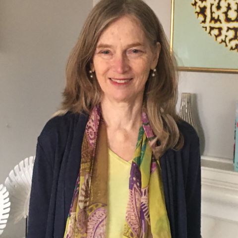 An image of Dr. Emily Hill wearing a yellow shirt and a colourful scarf