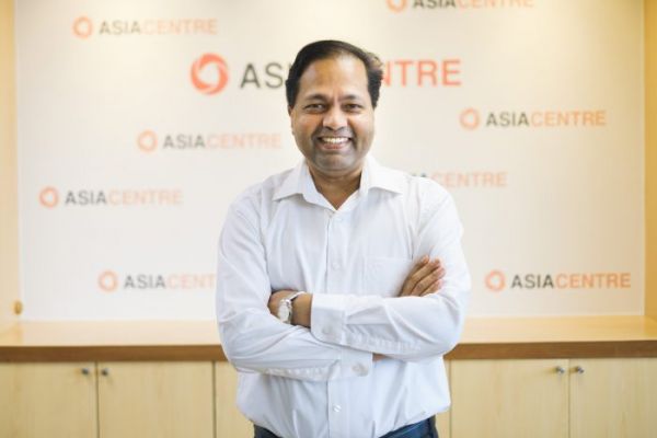 Image of Robin smiling in front of a background that reads Asia Centre