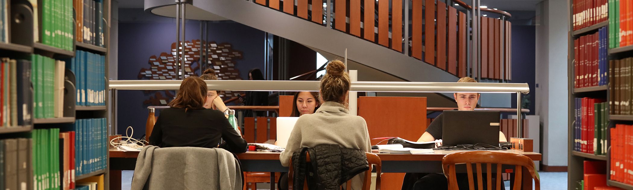 Students studying in Stauffer Library between the shelves of books 