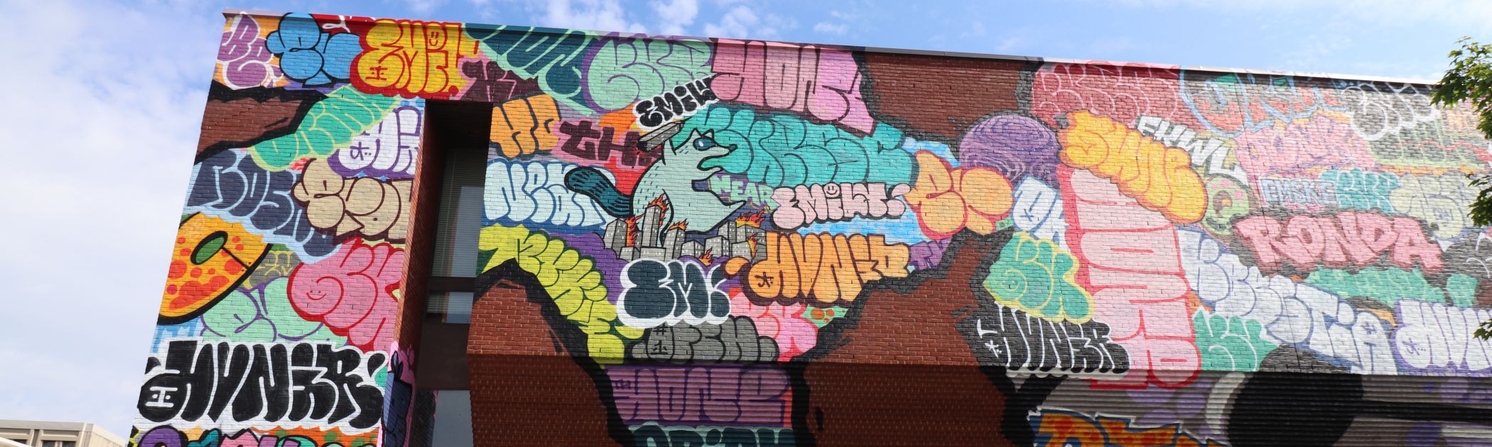 An exterior photograph of the Agnes Etherington Art Centre showing a brick wall covered in graffiti art