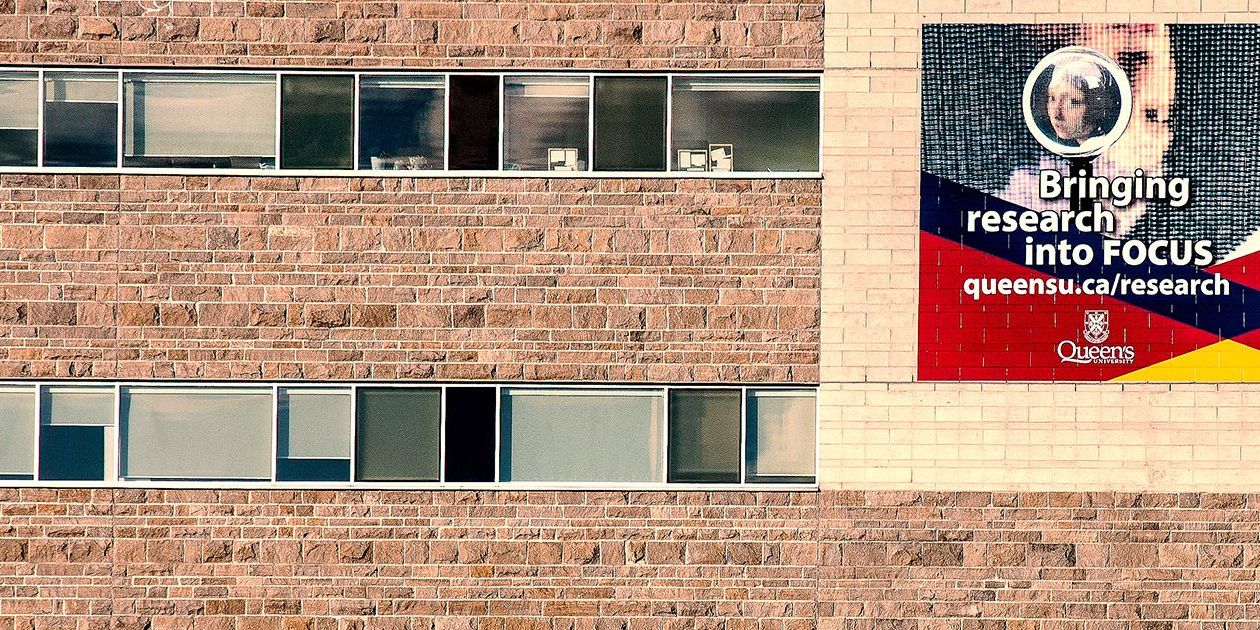 An image of a wall on Queen's campus with a painted image that says "Bringing research in focus"