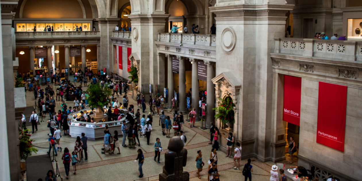 An image of the Met Museum with high stone arches and many visitors