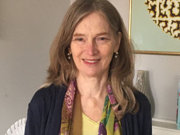 An image of Dr. Emily Hill wearing a yellow shirt and a colourful scarf