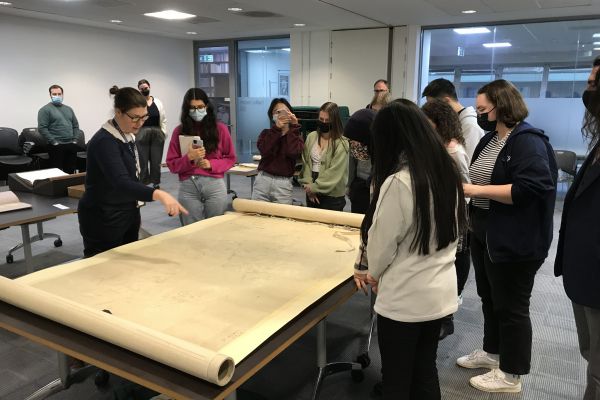 An image of students in an archives gathered around a map