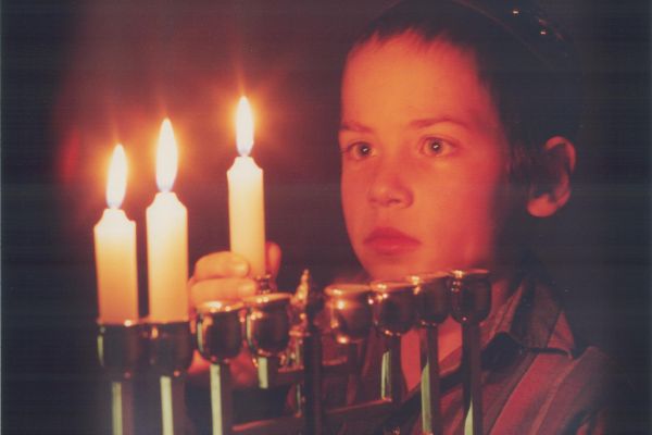 A photo of a young child lighting a menorah