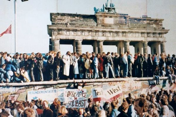 An image of a crowd standing on the Brandenburg Gate in Germany in 1989