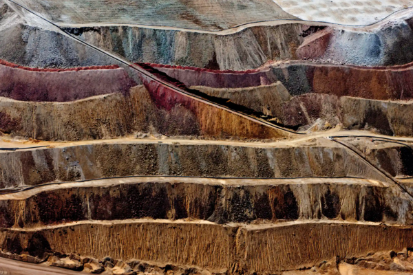 An image of copper mining taking place in New Mexico, featuring many deep layers of copper in a pit