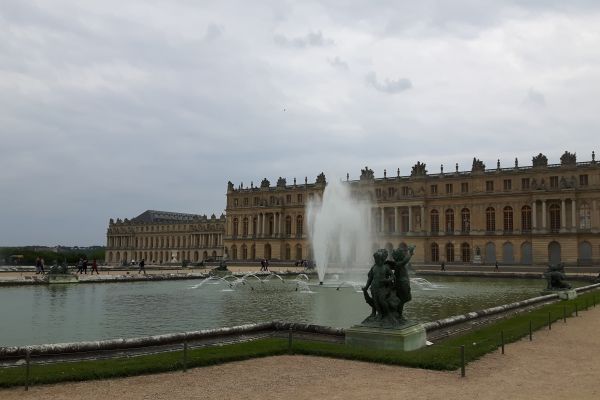 A photograph of the Palace of Versailles in France, with a grand water fountain on the lawn