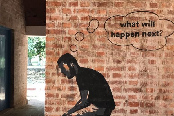 Graffiti on a brick wall in Havana. The image is of a man sitting with his head hanging forward, with a thought bubble that reads "what will happen next?"
