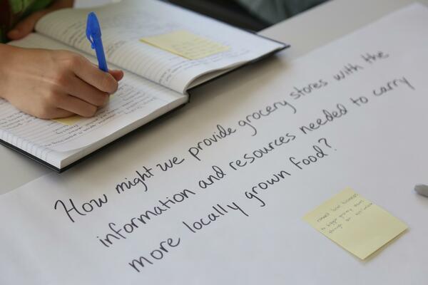 Student writes in notebook about a "how might we" question