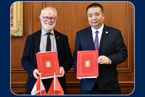 Two university leaders in formal attire hold red folders with a gold crest, standing in front of a wood-paneled wall with Canadian and Chinese flags in the foreground.