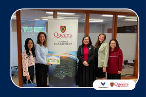 VinUniversity delegation and Queen’s University staff standing beside a Queen’s Global Engagement banner during campus visit.