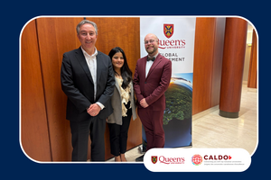 Three people stand indoors beside a Queen's University Global Engagement banner, posing for a photo. Queen's University and CALDO logos appear at the bottom right