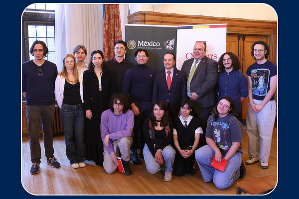  group of students and faculty pose for a photo indoors at an event.