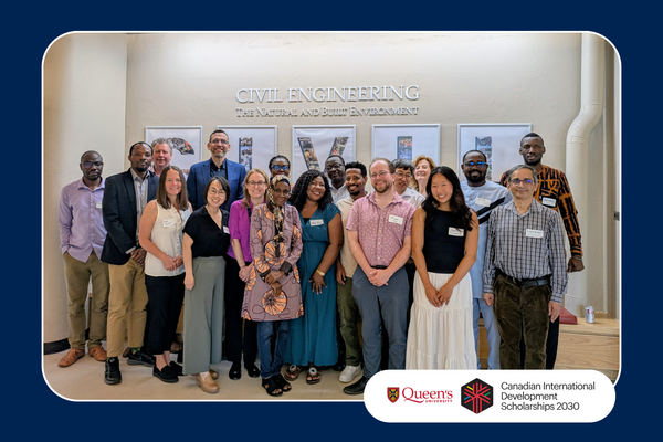 Community members posing in front of a "Civil Engineering" sign at Queen's University.