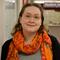 Headshot of Emma Eberl. A woman with glasses wearing a bright orange scarf, smiling against a neutral background.