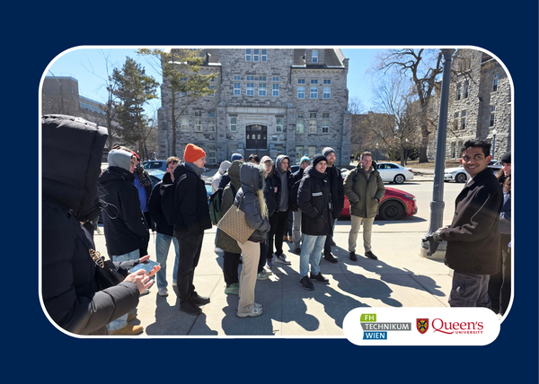 A group of people in winter clothing stand outside a historical stone building under a clear blue sky. Logos of FH Technikum Wien and Queen's University are displayed.