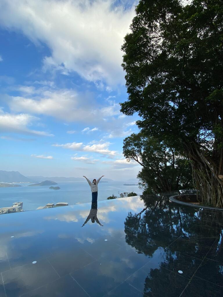student is standing in front of infinity pool and view of the sea behind