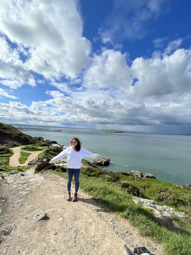 Michelle is standing by a cliff by a body of water