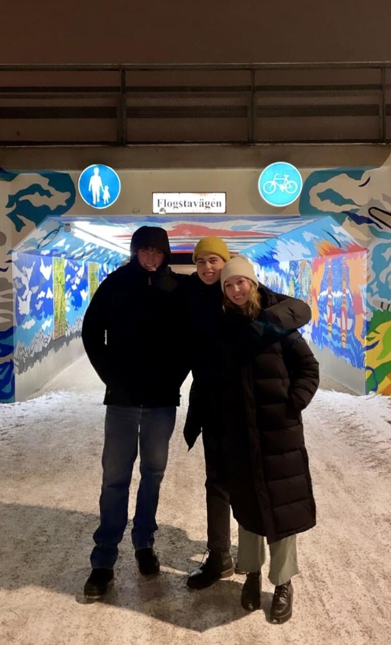 Alice posing with some friends in front of a colourful muraled tunnel