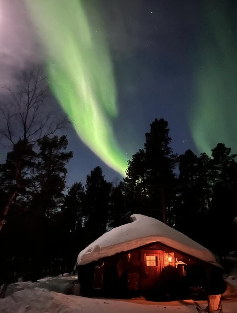 A snowy house with the northern lights above
