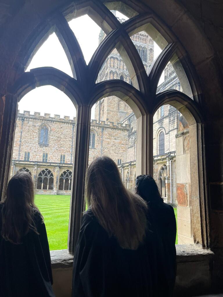 Patricia and friends are peering out an old window into the school's grassy courtyard