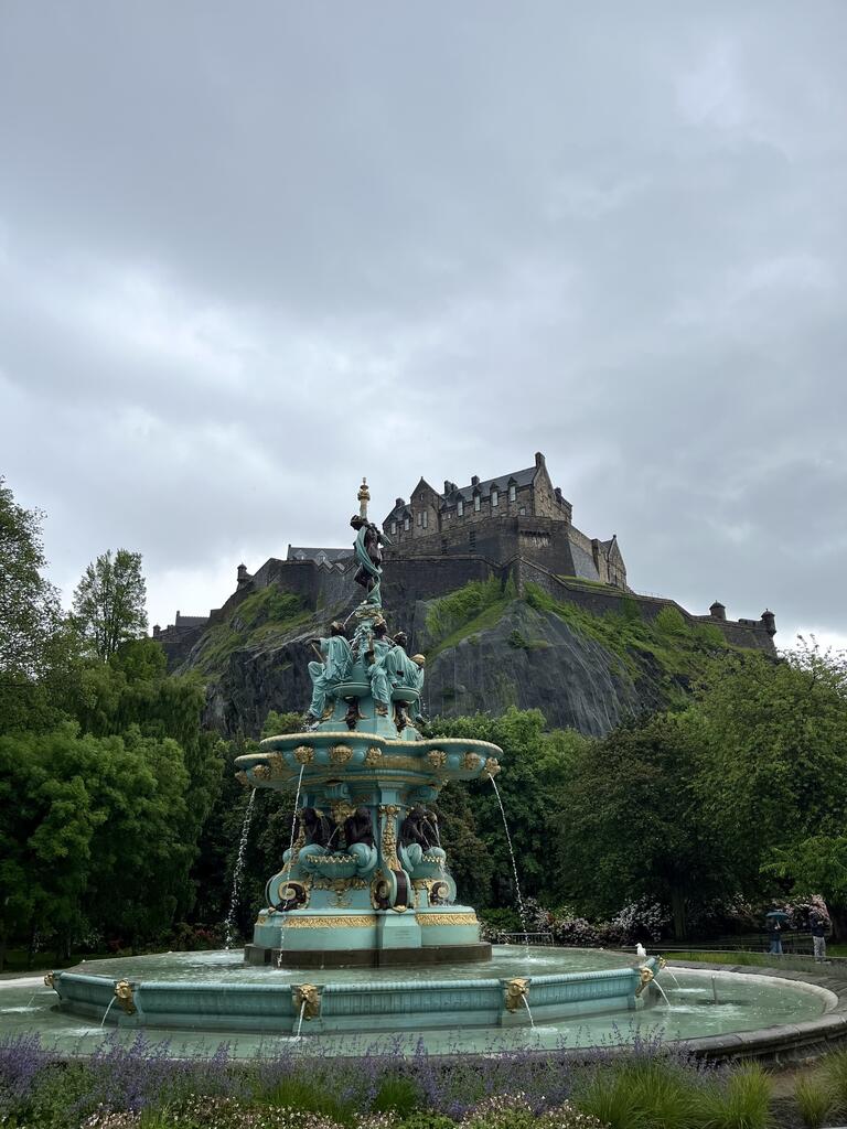 A green fountain in front of a castle on a hill